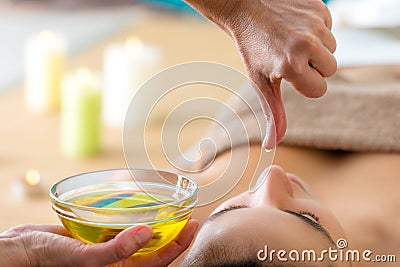 Aromatic oil dripping from finger at Ayurvedic massage. Stock Photo